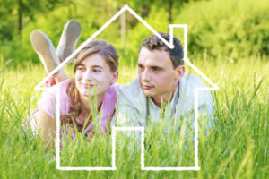 Young couple lying on grass dreaming to a house wondering what AC seer ratings are